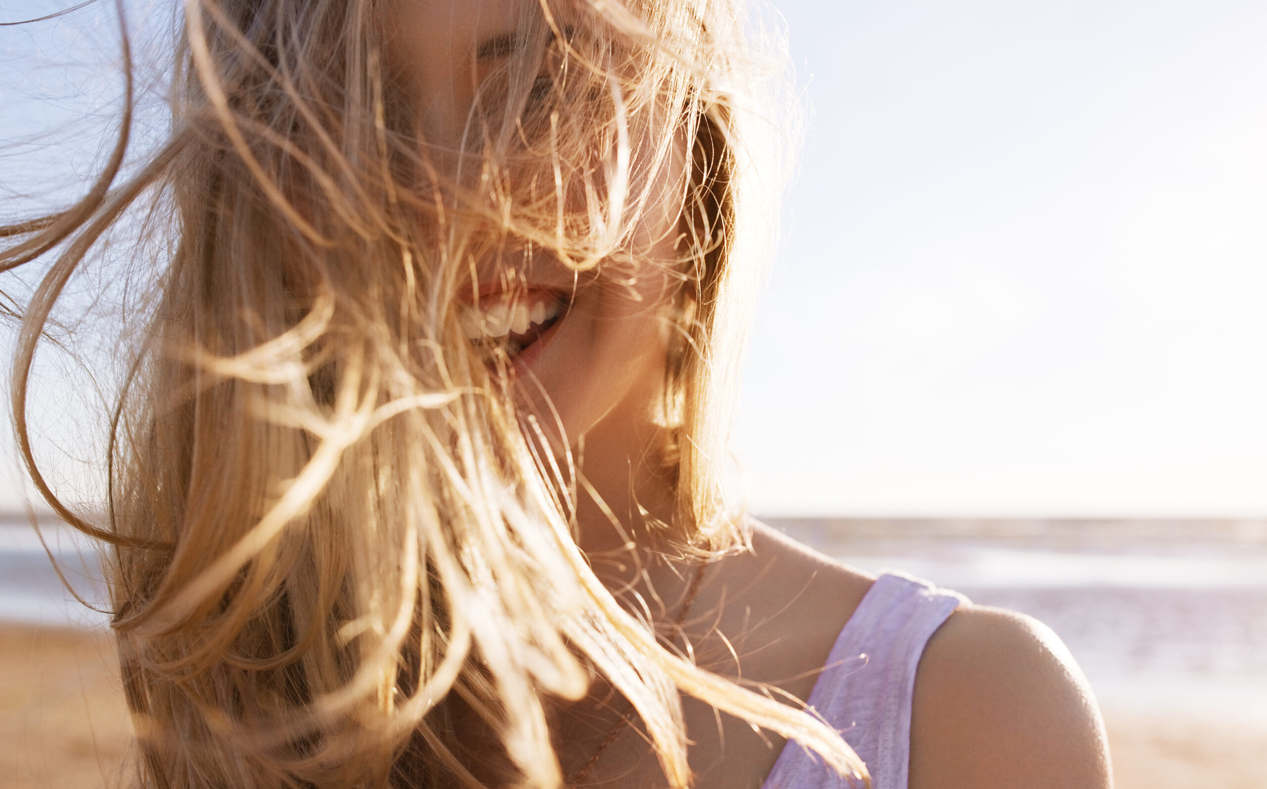 Eine lachende Frau vor einem Strand