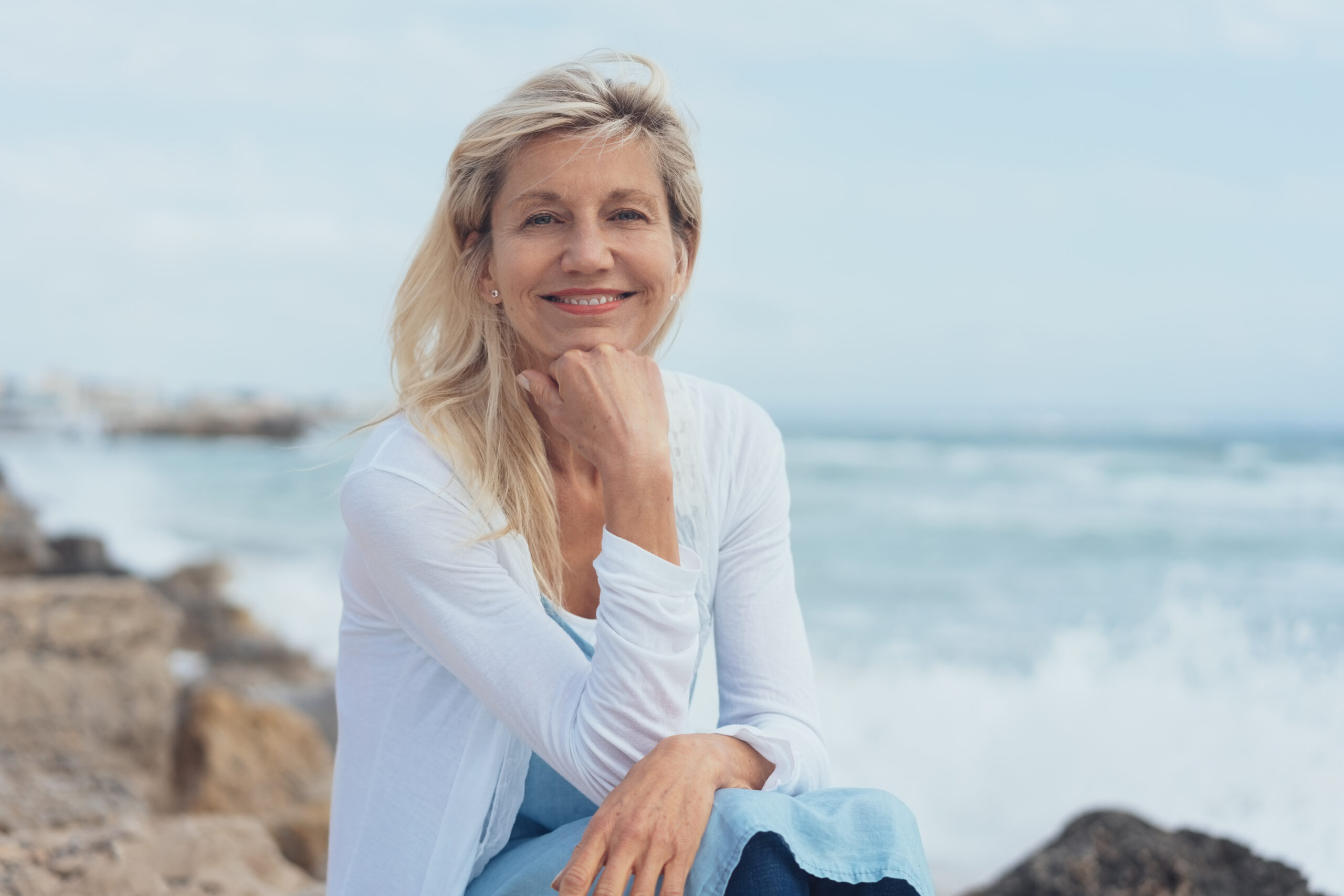 Une femme assise sur une plage rocheuse